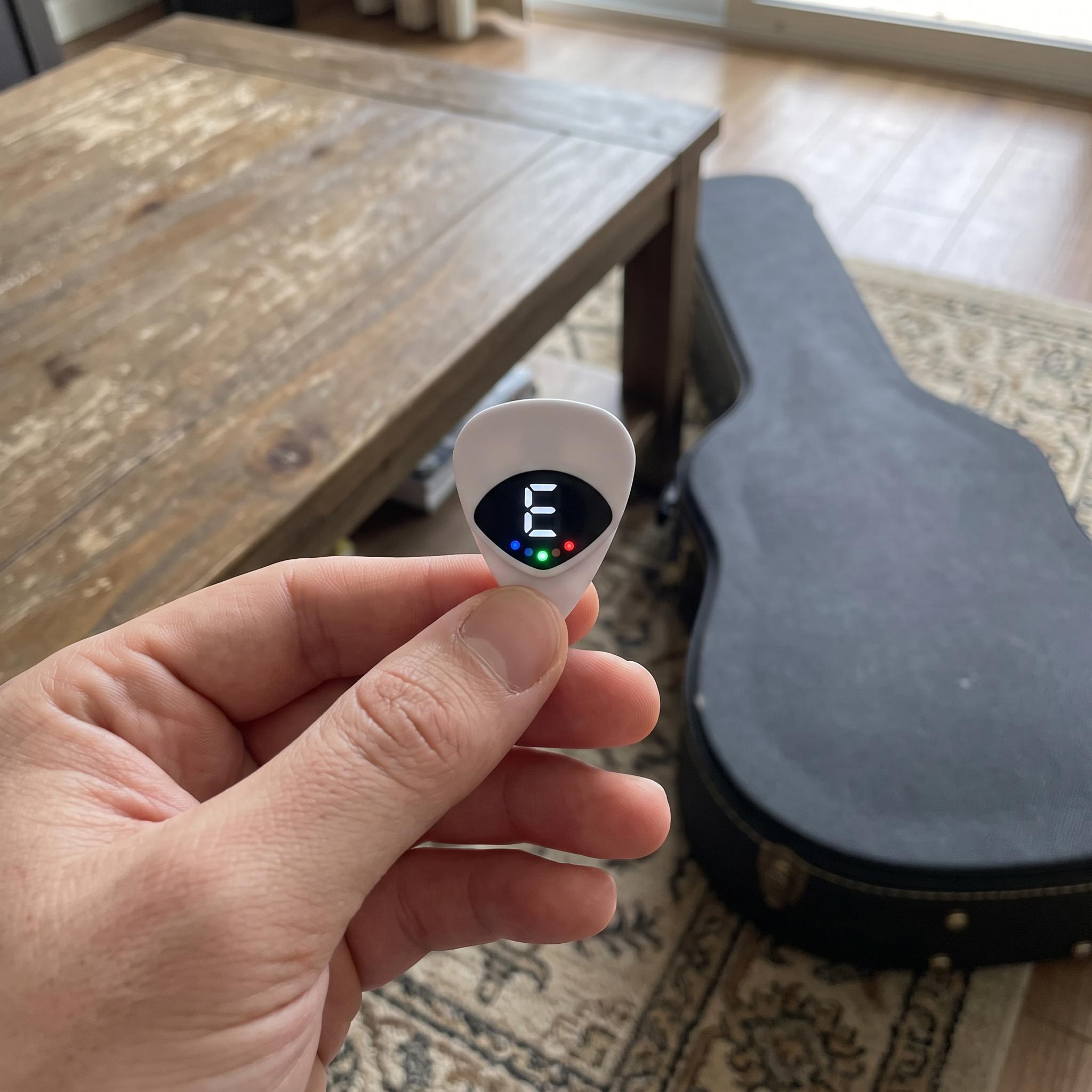 Pick tuner resting near guitar strings