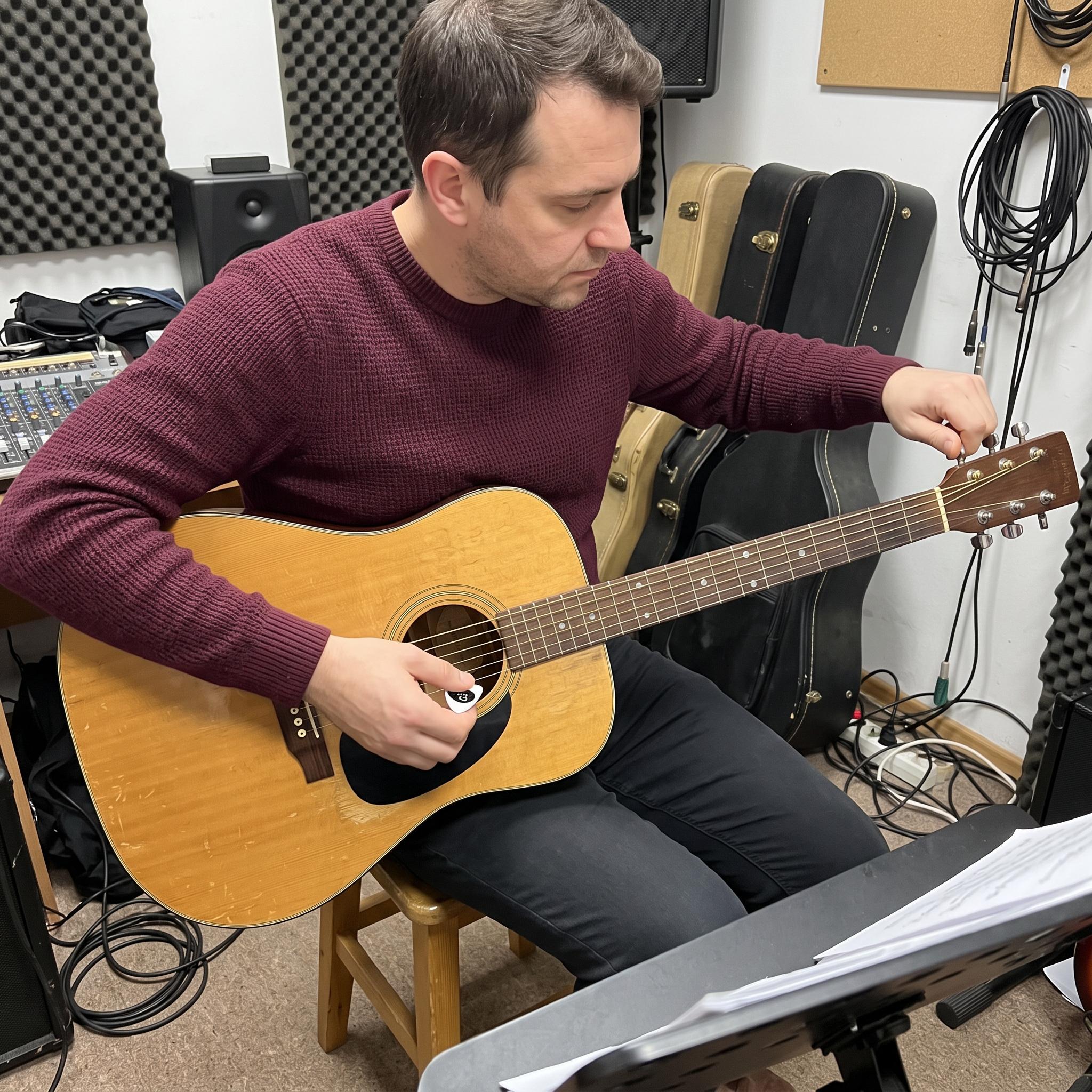 White pick tuner beside a guitar on a sofa