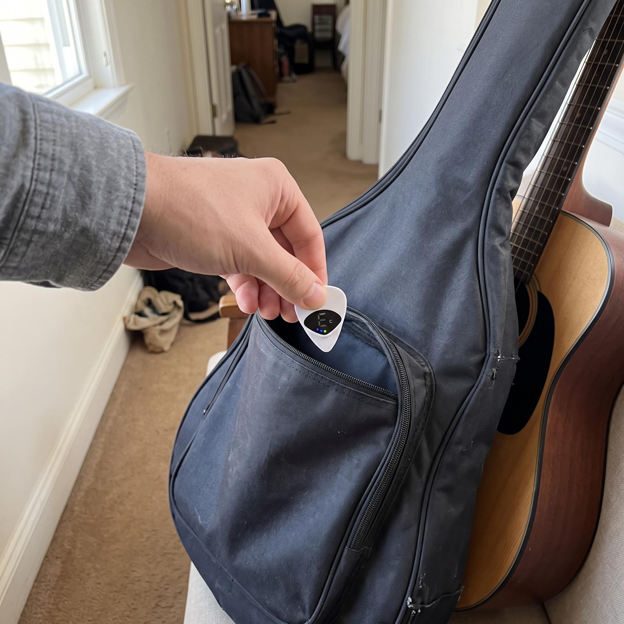 Hand packing a white Chordwell pick tuner in a guitar gig bag